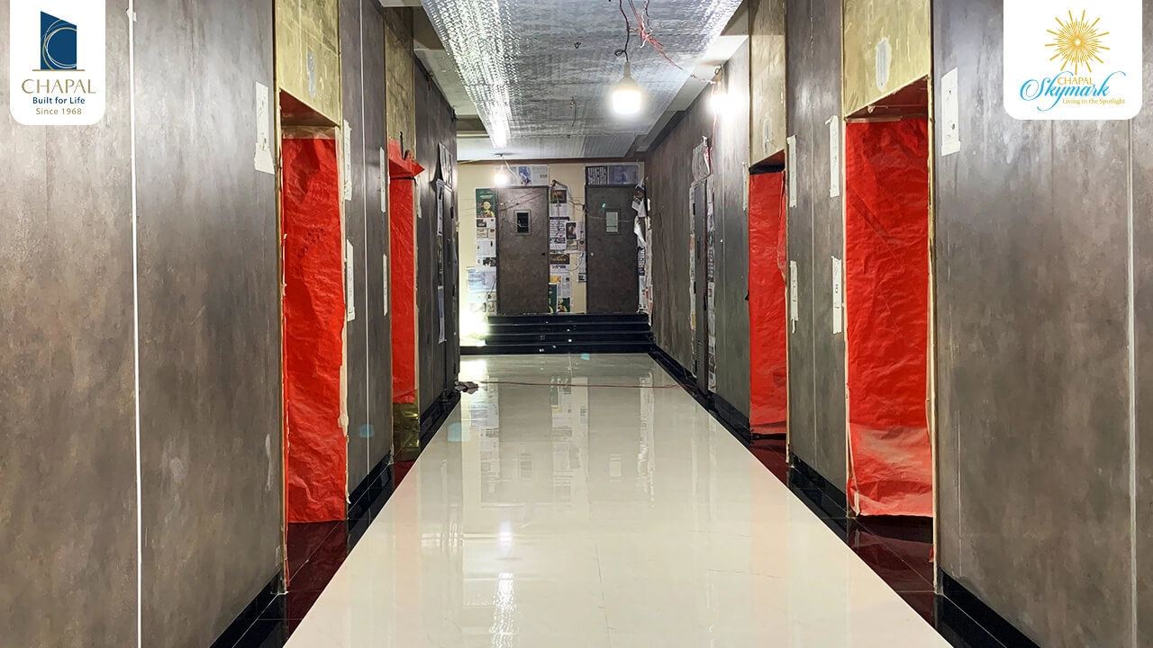 Spacious corridor in Chapal Skymark 50-storey tower with polished floors, red protective sheeting, and branded walls