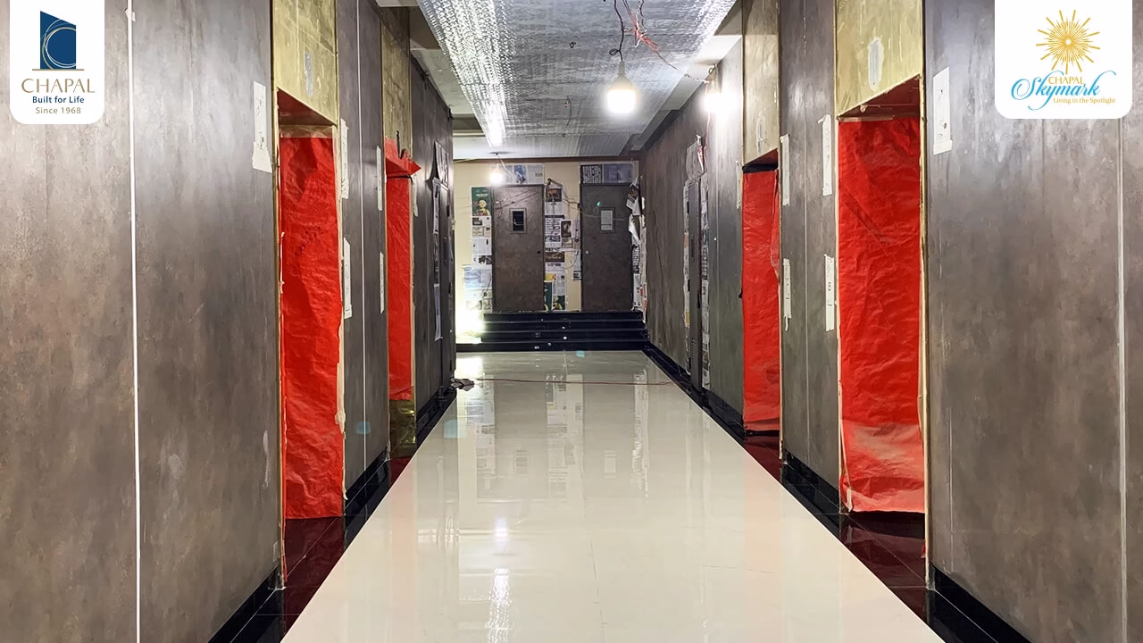Spacious corridor in Chapal Skymark 50-storey tower with polished floors, red protective sheeting, and branded walls